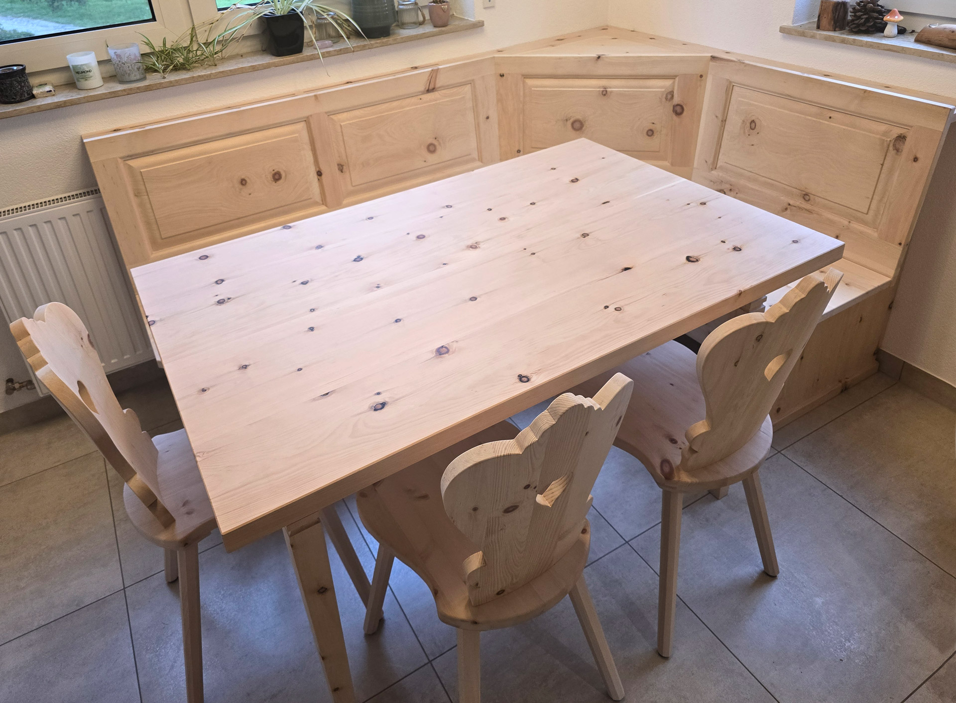 Sitzgruppe aus Zirbe mit Eck-Sitzbank, Tisch und Stühlen mit Herzausschnitt an der Lehne