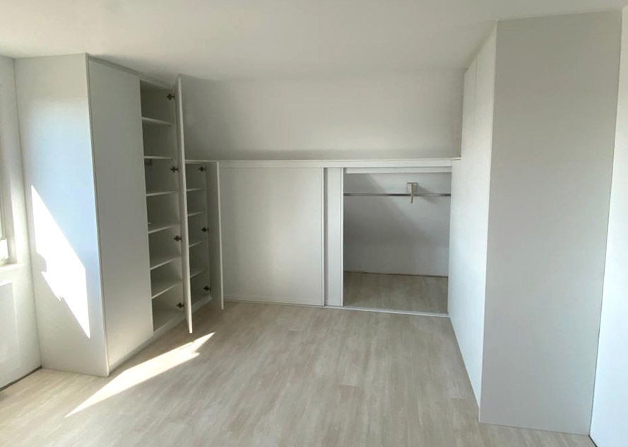 Einbauschrank unter Dachschräge in weiß mit geöffneten Türen
