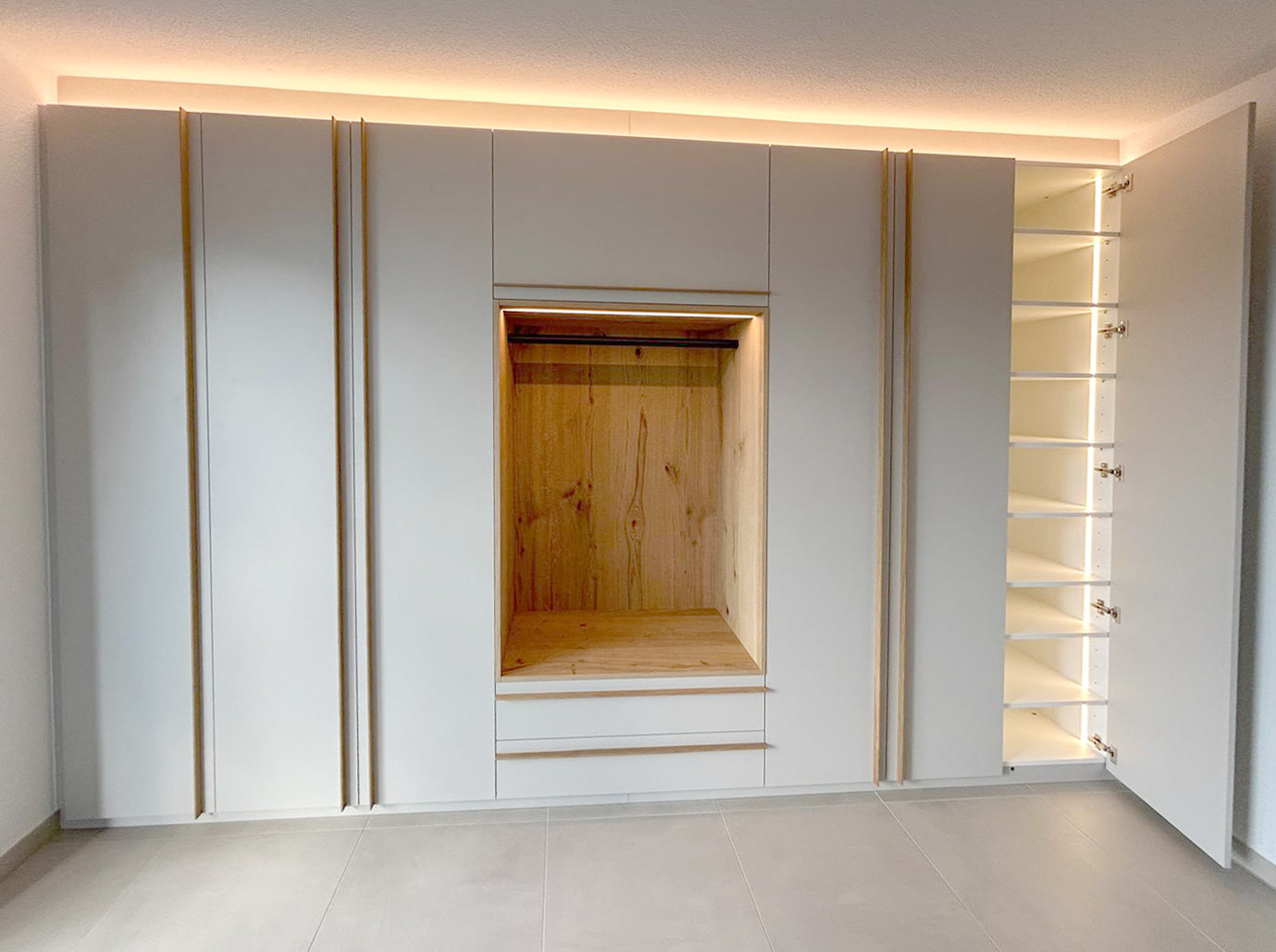 Garderoben Einbauschrank in Cashmere Grau lackiert. Griffleisten aus Eiche. Integrierte Beleuchtung.