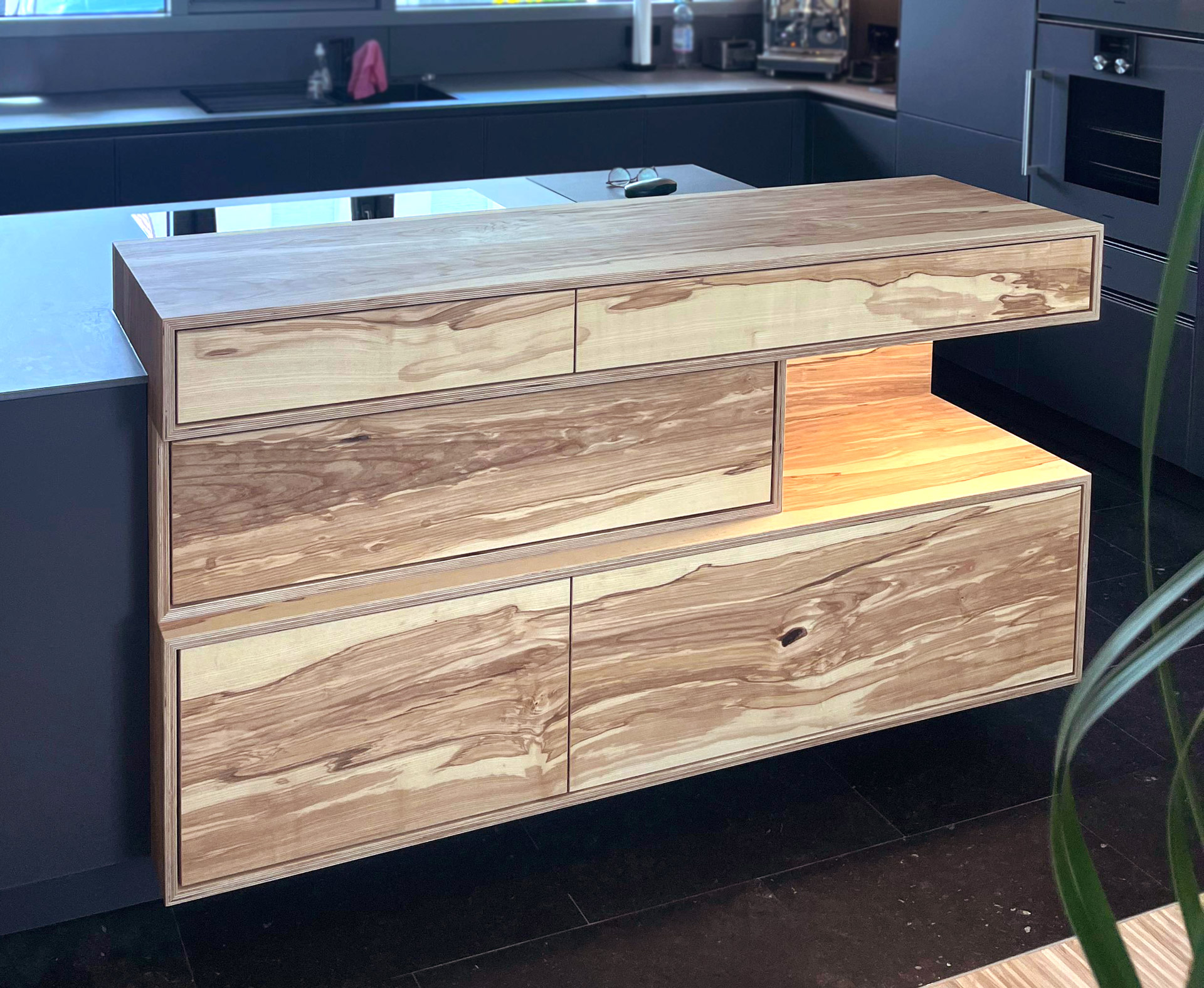 In Küche integriertes Sideboard. Multiplex mit Olivesche furniert und matt lackiert. Elektrische Schubladen und integrierte Beleuchtung