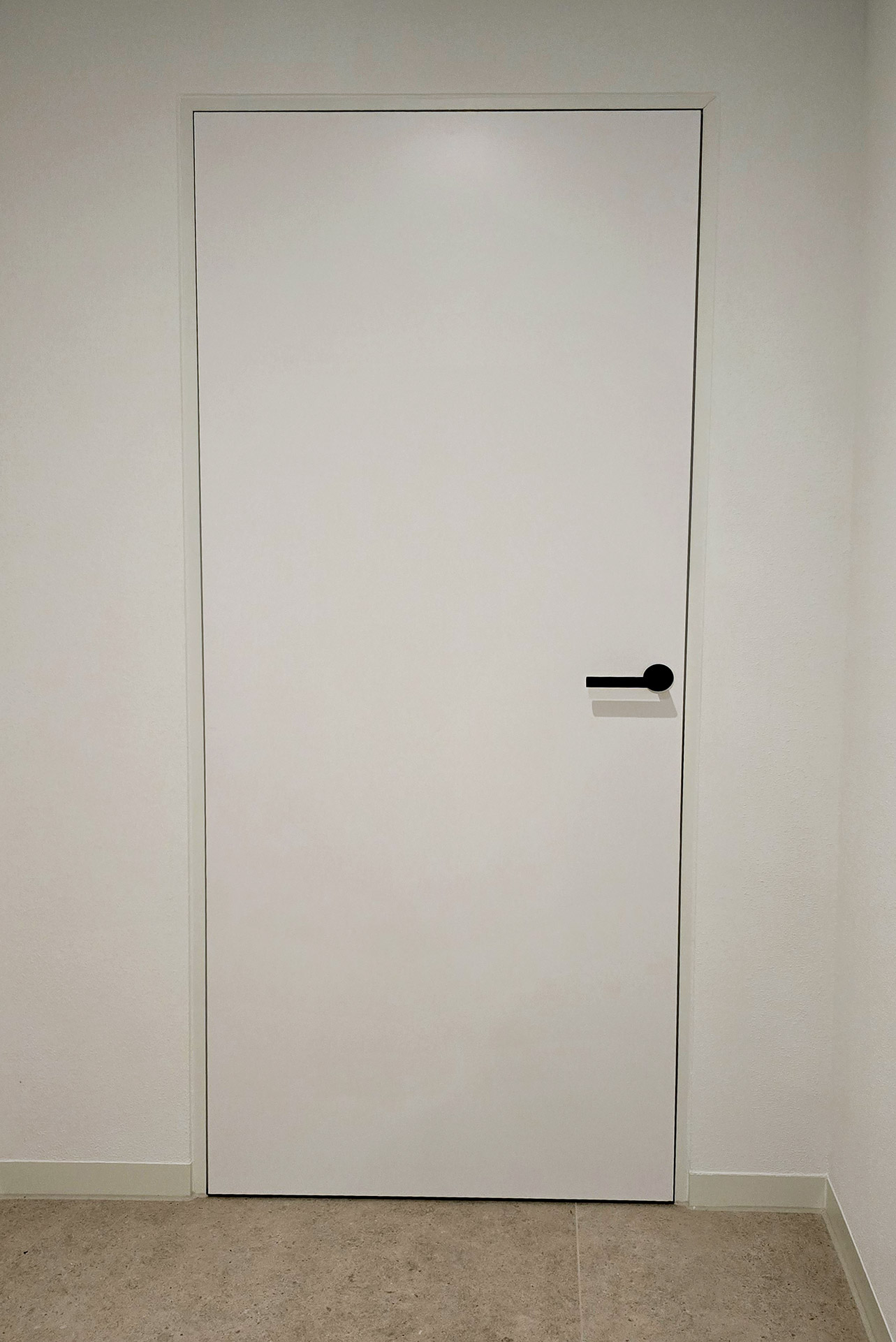 Weiße Zimmertür mit schwarzem Griff